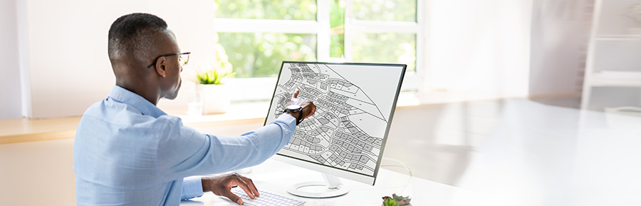 Man at a desk pointing to an area on his monitor